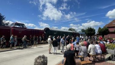 Zug der Bleckeder Kleinbahn an der Haltestelle Erbstorf Ziegelei, Menschen winken, FDP-Fahne, Sonnenschein, Familienatmosphäre